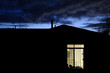 © DAVID VEENTJER/Austockphoto - A house at night with a light on in one room