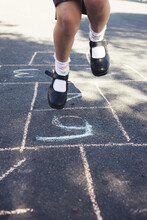 Girls Legs Jumping On A Hopscotch Game