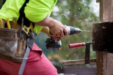 A Tradesman Drills Into A Wooden Beam.