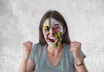 Young woman with painted flag of America state Maryland looking energetic with fists up