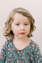 Little Toddler Girl With Curly Hair In Front Of Neutral Background