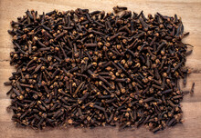 Top View Of Pile Of Aromatic Dried Cloves Buds, Wood Background
