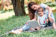 © zadorozhna - Mother with son sitting in the park and work on laptop.