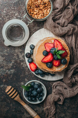 Wall Mural - American pancakes with fresh berry and granola on metal background. Summer homemade breakfast.