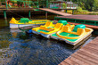 Pedal boats or paddle boats catamarans station. Yellow water bicycles locked at lake marina dock pier on sunny summer day. Summer leisure activity outdoors.