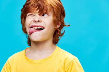 Wall Mural - grimacing red-haired boy showing tongue squinting one eye looking sideways 