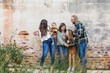 © Ursula Page - A family of five with two girls and a baby boy standing by an urban old brick wall and laughing and playing together