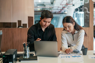 Wall Mural - Young asian business people working together to idea of ​​collaboration using laptop and table at the office.