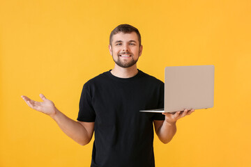 Wall Mural - Young man with laptop on color background