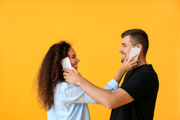 Wall Mural - Young couple with mobile phones on color background