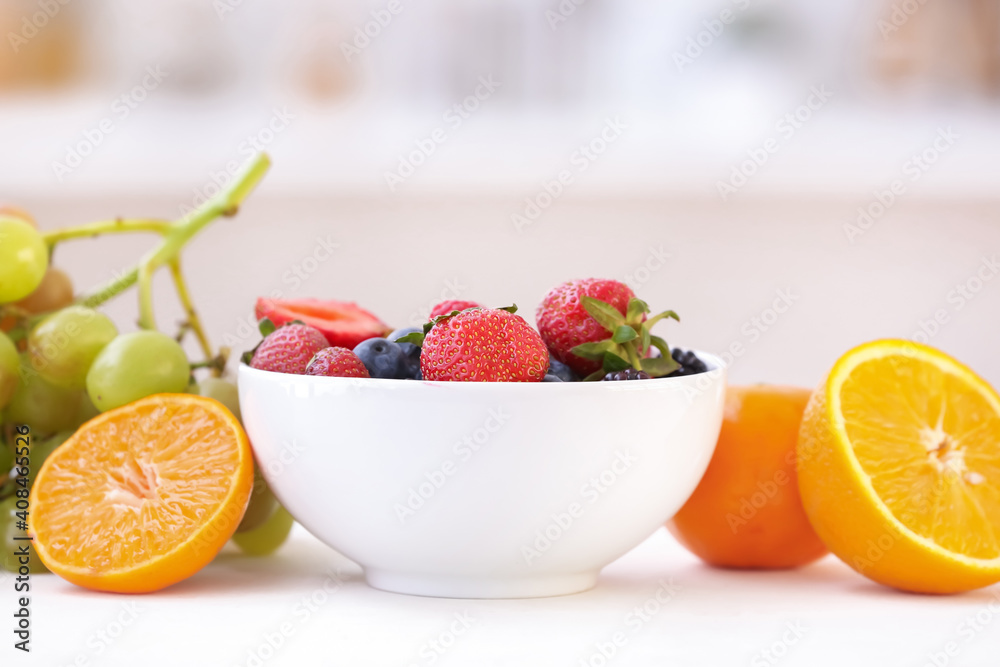 Bowl with different berries and fruits on table