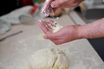 Close up human hands making pastry from raw dough/ Bread making process. Closeup of man hands kneading dough. Baker cooking pastry. Culinary courses and food preparation.