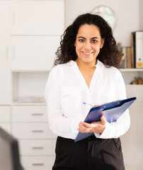 Wall Mural - Elegant female assistant with clipboard politely welcoming to modern company office