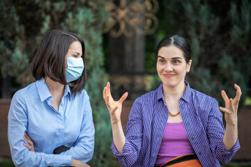 Two young women with different attitudes to coronavirus.