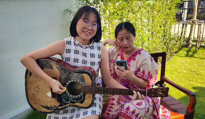 Woman and girl enjoy life and playing guitar.