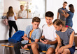 © JackF - Group of three teenage schoolmates with smartphones on break in college