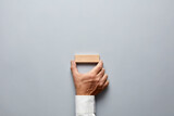 Fototapeta  - Businessman hand holding a blank wooden block on gray background.