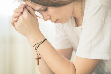 Hands folded in prayer on a Holy Bible in church concept for faith, spirituality and religion, woman praying on holy bible in the morning.