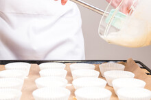 Closeup Of The Cook Pouring Cheesecake Batter Pouring Into Cupcake Liners On A Sheet Pan