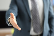 Man in business suit giving his hand for handshake closeup