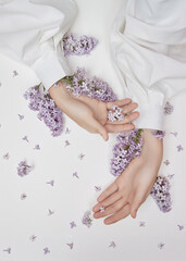 Wall Mural - Natural woman cosmetics for hands made of lilac flowers and petals. Moisturize and soften the skin of the hands. Lilac flowers protrude from the sleeves of the arm