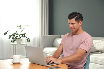 Poster - Man using laptop for search at wooden table in living room