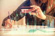 © peshkova - Double exposure of woman on-line shopping holding a credit card and financial graph drawing. Stock market E-commerce concept.