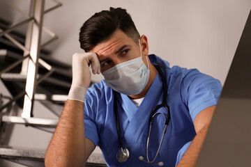 Poster - Sad doctor in facial mask on stairs indoors. Stress of health care workers during coronavirus pandemic