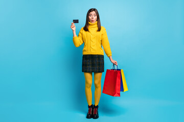 Sticker - Full length photo of cute shocked young lady wear yellow sweater holding credit card bargains isolated blue color background