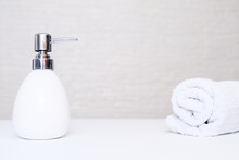 Bathroom Background, Toilet Accessories For Hand And Body Care, Liquid Soap Dispenser And Towels Against Light Background