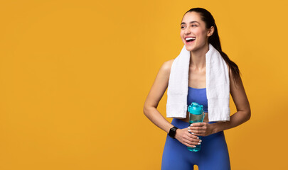 Sporty woman looking aside at copy space holding water bottle