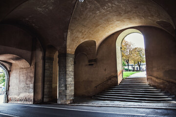 Wall Mural - Pedestrian tunnel, old stone arched doorway and road in a European city.