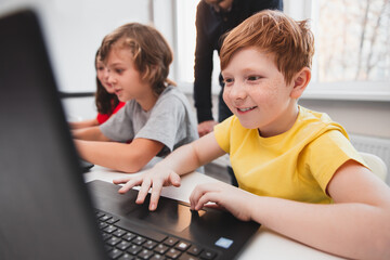 Excited boy working with laptop in classroom