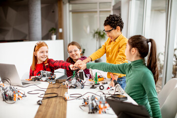 Wall Mural - Happy kids programming electric toys and robots at robotics classroom