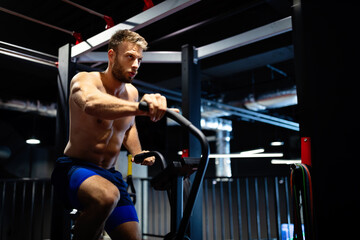 Wall Mural - Portrait of a handsome man workout on a fitness machine at gym