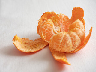 Wall Mural - Fresh juicy bright orange tangerines with green leaves on a white cotton tablecloth in the morning light