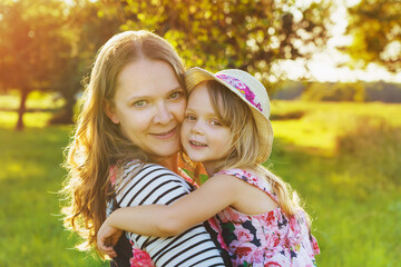 Wall Mural - Pretty smiling girl and mother relaxing outdoor