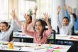 © Prostock-studio - Diverse small schoolchildren raising hands at classroom