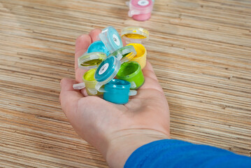 Wall Mural - The boy holds multicolored paints in his hand. Hand close up on a wooden table background.