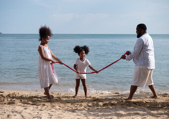 Happy African American family playing tug of war at the beach. People lifestyle travel on vacation concept. .