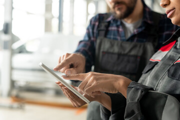 Poster - Hand of young female worker of car maintenance center pointing at tablet display