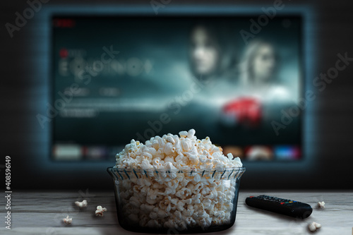 Video streaming app on tv screen behind a bowl of popcorn and a remote control.