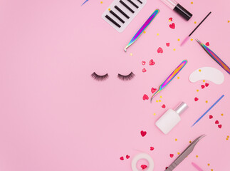 Wall Mural - Eyelash extension tools, artificial eyelashes and red hearts on a pink background. Tools for the lashmaker. Top view, copyspace.