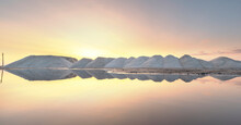 Sea Salt Production Near Pomorie Salt Lake, Bulgaria. Piles Of Salt In Factory At Sunset With Reflection In The Water. 