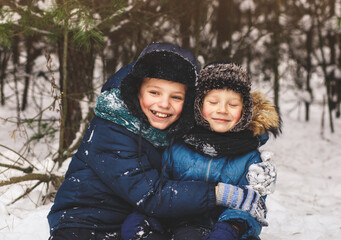 Two boys in the winter in nature cuddle. Two brothers have fun outdoors