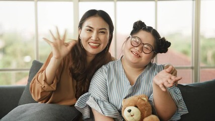 Wall Mural - Down syndrome girl and mother smile happily looking camera. happy adopted down syndrome girl and Asian mother waving hand greeting and smile in front of camera. Down syndrome girl doing activity.