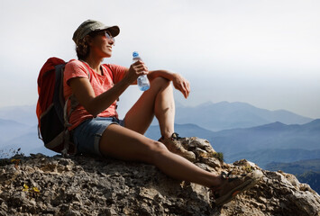 Female tourist in mountains with a bottle of drinking water