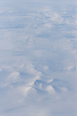 Canvas Print - Aerial view of snow-capped mountains and clouds. Winter snowy mountain landscape. Icheghem Range, Kolyma Mountains. Magadan Region, Siberia, Far East of Russia. Great for backgrounds.