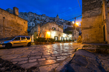 Wall Mural - Night view, street level of an illuminated cafe in the historic, medieval center of the ancient city of Matera Italy.