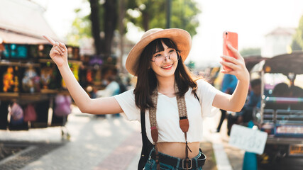 Wall Mural - Young adult tourist asian woman using smart phone for selfie with temple background at outdoor on day